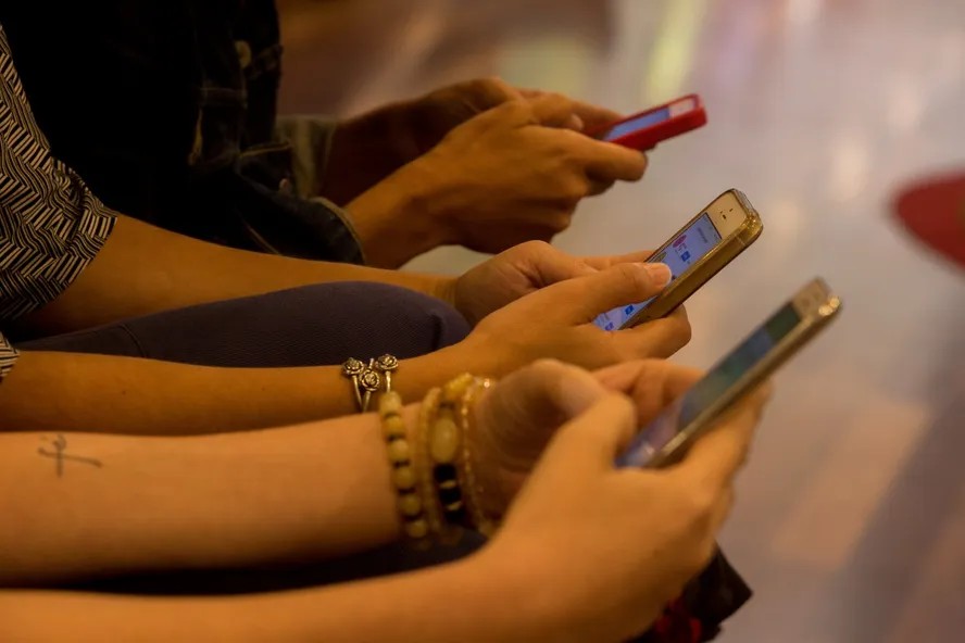 Close na mão de várias mulheres usando celulares