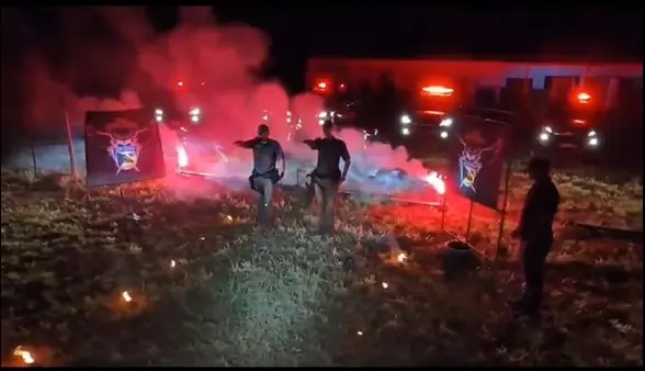 Vídeo com música dramática exibe supostos policiais com braços em riste e uma cruz em chamas, símbolo usado pela organização supremacista Ku Klux Klan | Foto: Reprodução