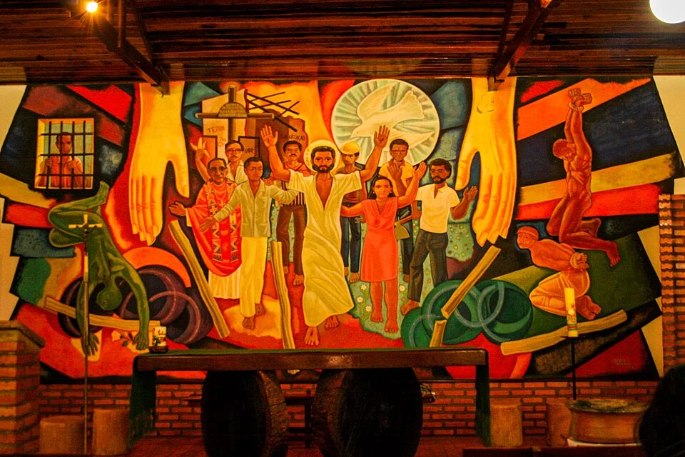 Imagem de um dos murais da série Murais da Libertação, de Maximino Cerezo Barredo, que relaciona fé e crítica social. A obra retrata conflitos sociais da América Latina, como a violência no campo e a desigualdade. Foto: Wikimedia