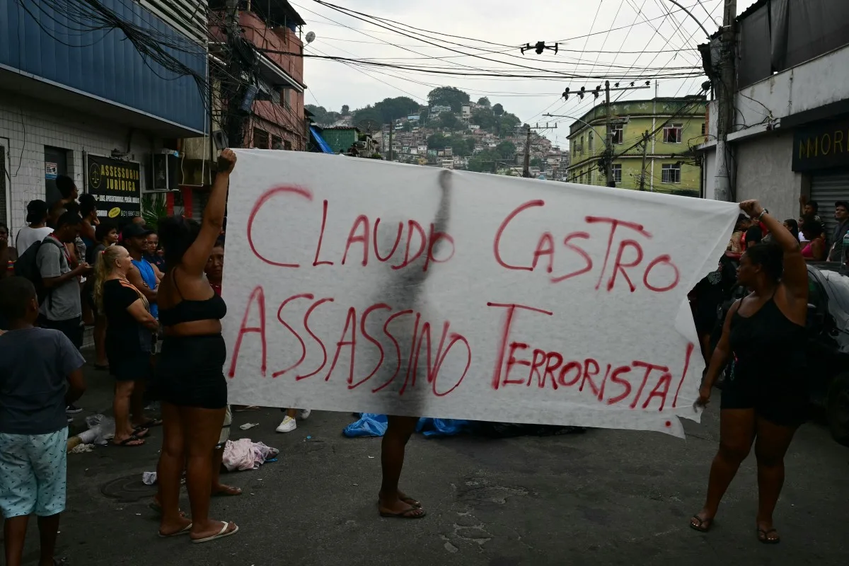Pessoas protestam enquanto moradores enfileiram corpos na Praça São Lucas, na favela Vila Cruzeiro, Complexo da Penha, Rio de Janeiro, Brasil, em 29 de outubro de 2025, após a Operação Contenção | Crédito: Pablo Porciuncula/AFP.