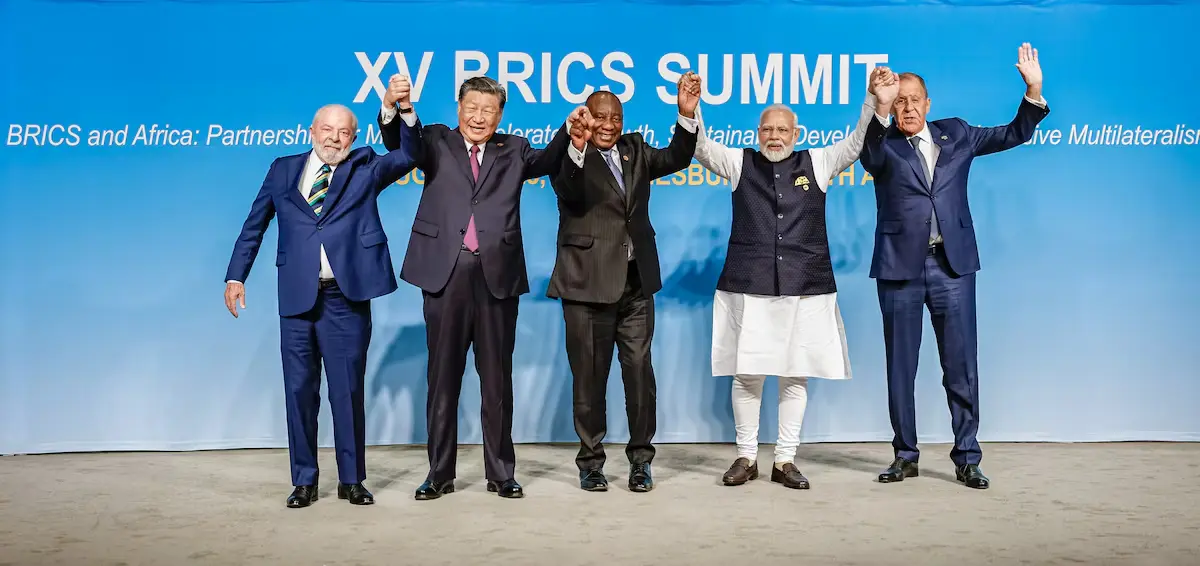 Os líderes do Brasil, China, África do Sul, Índia e o representante da Rússia (Lula, Xi Jinping, Ramaphosa, Modi e Lavrov) posam de mãos dadas durante a 15ª Cúpula do BRICS. Representa a união política do Sul Global.
