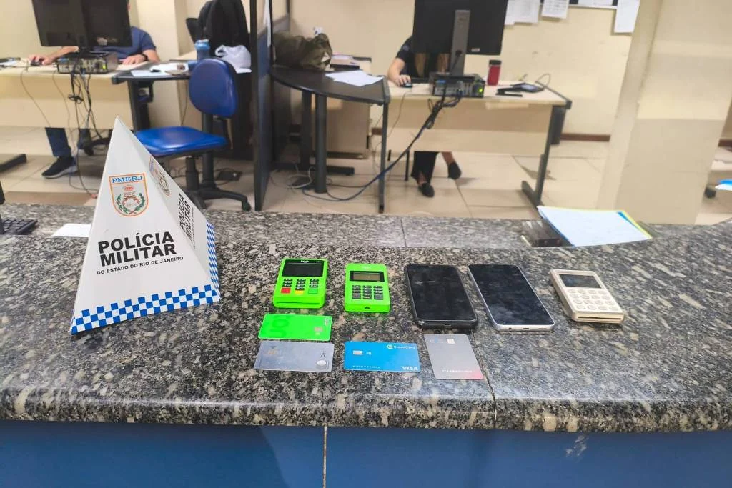 Máquinas de cartão, celulares e cartões bancários apreendidos pela polícia após a prisão de um taxista suspeito de tentar cobrar R$ 3,4 mil de um casal de turistas alemães por uma corrida em Copacabana, na zona sul do Rio; segundo a PM, o trajeto custaria cerca de R$ 40 - Divulgação/PMERJ