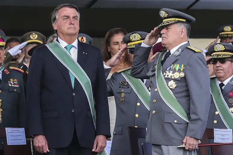 Fotografia colorida de Jair Bolsonaro usando a faixa presidencial ao lado de um general de farda cinza que presta continência. Simboliza a reaproximação entre o poder executivo e as cúpulas militares no período recente.