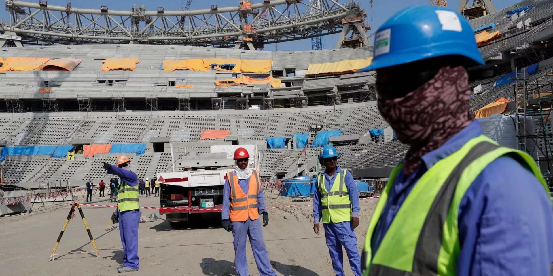 Trabalhadores migrantes na construção dos estádios do CatarTrabalhadores migrantes com equipamentos de segurança em obra de estádio da Copa do M