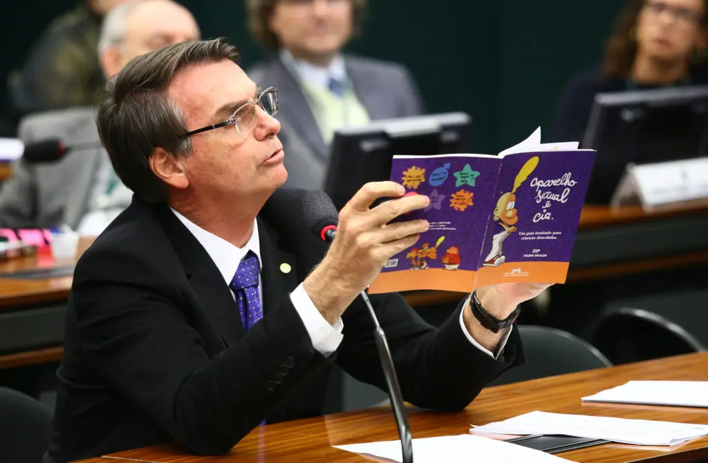 O então deputado federal Jair Bolsonaro segura e aponta para uma cartilha educativa sobre educação sexual durante sessão na Câmara dos Deputados. O material foi usado para criar a narrativa de um suposto “kit gay” usado como recurso pedagógico. Foto: Antonio Augusto/Câmara dos Deputados