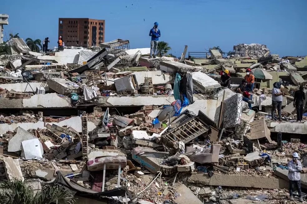 Voluntários buscam sobreviventes em meio a escombros de prédios destruídos por terremotos em Caraballeda, no estado de La Guaira, na Venezuela, em 28 de junho de 2026. — Foto: Miguel Medina/Pool/AFP