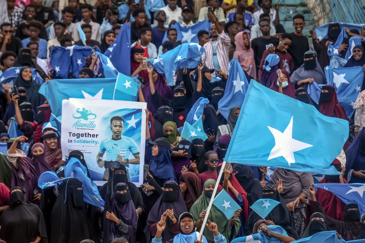 Apoiadores do árbitro somali Omar Abdulkadir Artan seguram bandeiras e cartazes durante recepção em Mogadíscio, nesta quarta-feira (10), antes de partida de solidariedade. | Crédito: Hassan Ali Elmi/AFP