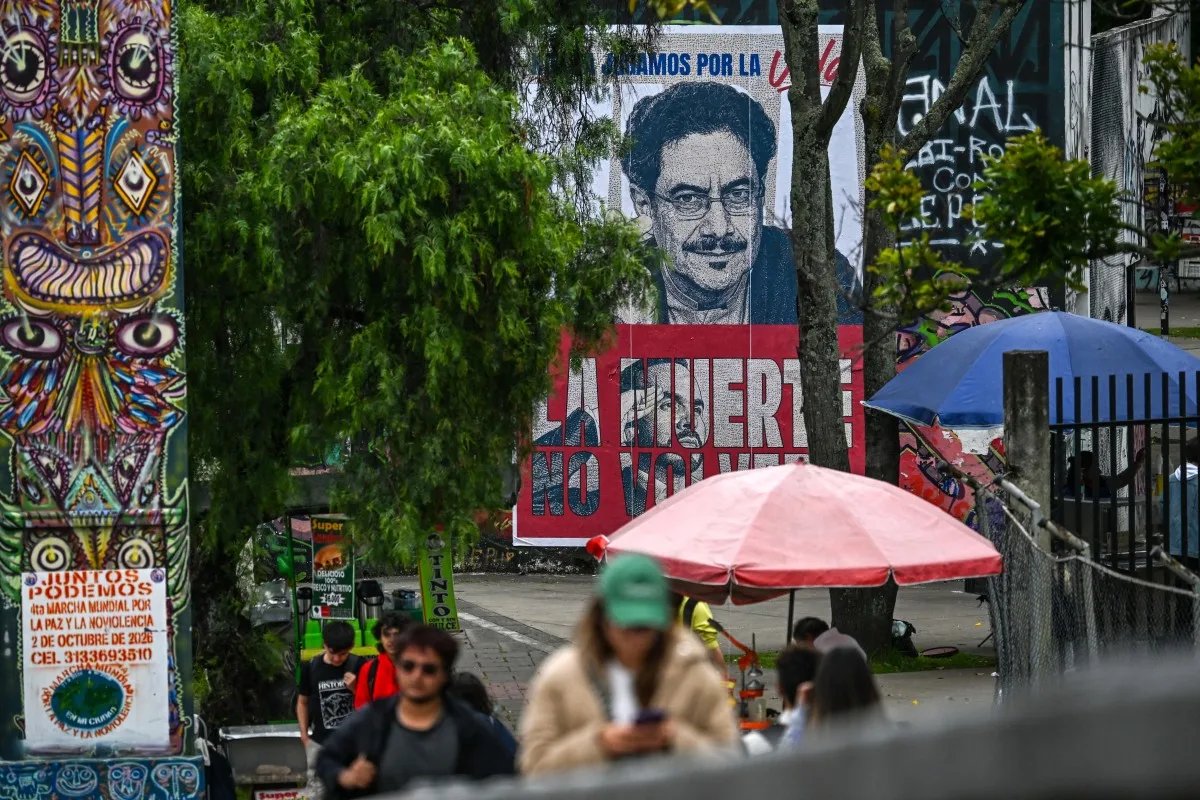 Pedestres passam por cartaz com imagens de Iván Cepeda e Abelardo de la Espriella em Bogotá, na Colômbia, na quinta-feira (19), antes do segundo turno presidencial. (Foto: Juan Barreto/AFP)