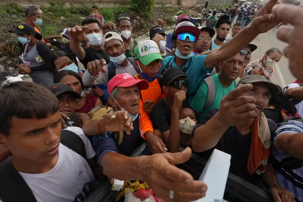 Pessoas recebem suprimentos de voluntários em La Guaira, na Venezuela, em 30 de junho de 2026 — Foto: Matias Delacroix/AP Photo