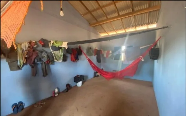 Alojamento de carvoaria de Ferinha em São Raimundo das Mangabeiras (MA). A fiscalização constatou que o empregador não fornecia camas, redes ou roupas de cama, obrigando os trabalhadores a custearem o próprio equipamento de repouso. O ambiente operava em desacordo com as normas de segurança e saúde, sem armários individuais e com instalações sanitárias precárias, marcadas pela falta de higiene, bacias sem tampo e ausência total de material para limpeza das mãos | Crédito: Reprodução/MTE