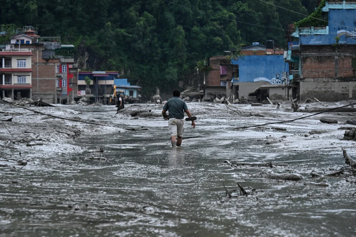 Um morador caminha por uma rua coberta de lama após enchentes repentinas e um deslizamento de terra em Devighat, no distrito de Nuwakot, Nepal, em 26 de agosto de 2026. Foto de PRAKASH MATHEMA/AFP