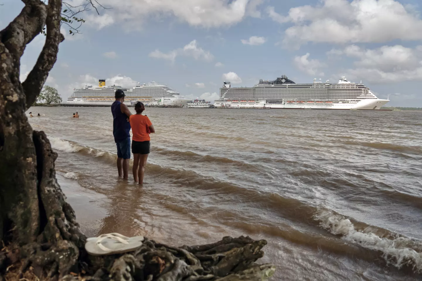 Pessoas em uma praia às margens do Rio Guama observam os navios de cruzeiro atracados no Porto de Outeiro, que receberá as delegações que participarão da COP30, a Conferência das Nações Unidas sobre Mudanças Climáticas, em Belém, Brasil, no dia 6 de novembro. (Carlos Fabal/AFP via Getty Images)