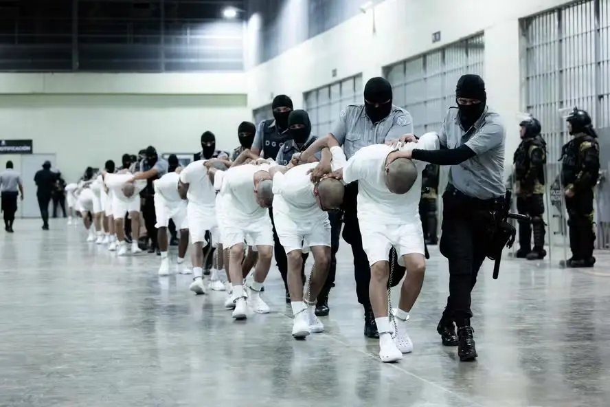 Detentos são conduzidos por agentes de segurança no Centro de Confinamento do Terrorismo (CECOT), megaprisão construída durante o governo Nayib Bukele e símbolo da política de encarceramento em massa. Foto: Presidência de El Salvador / AFP