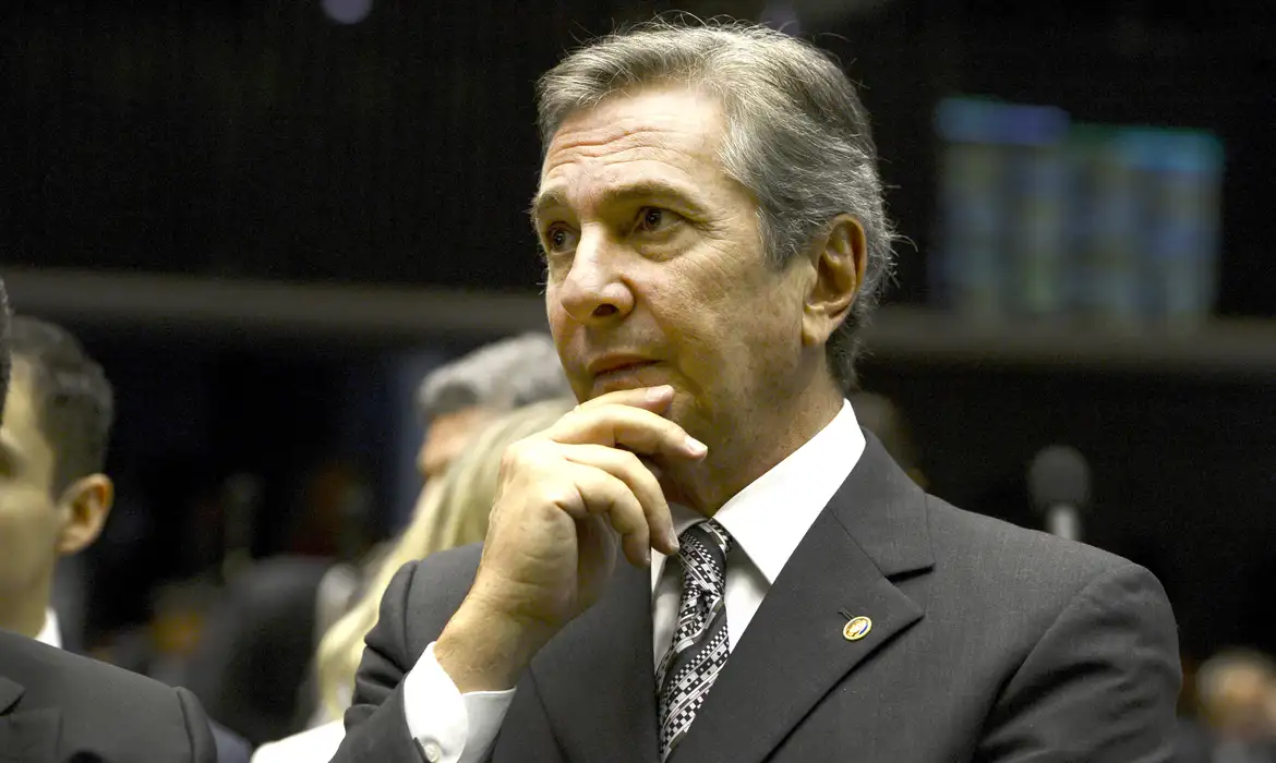 Fernando Collor, ex-presidente da República, sentado e vestindo terno escuro e gravata, com uma das mãos apoiada no rosto, durante sessão no Congresso Nacional.